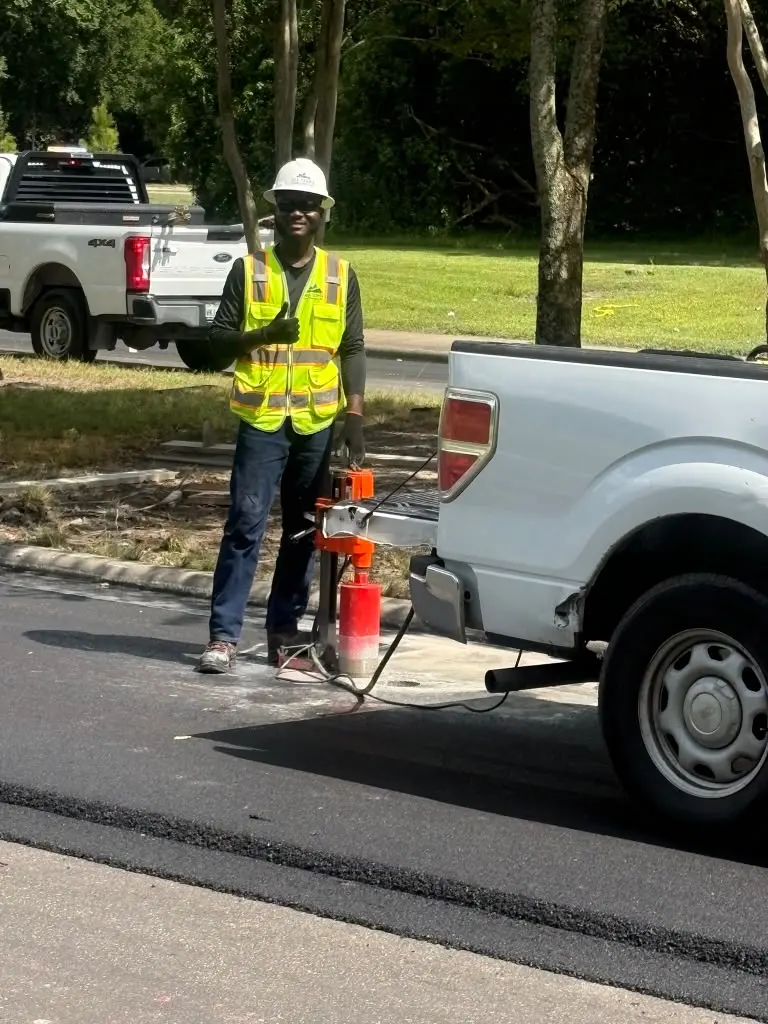 Crew member coring pavement beside work truck
