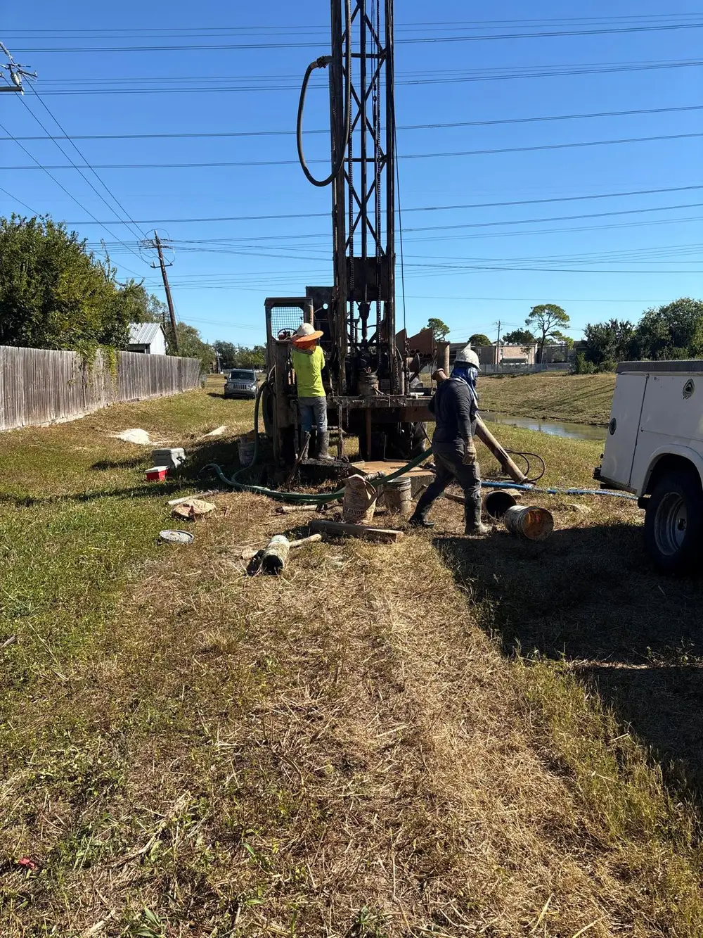 Drill rig and crew completing a borehole with monitoring pipe installed