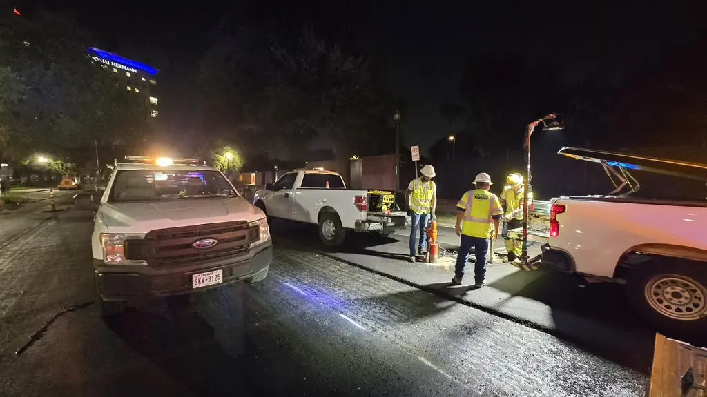 Three crew members setting up a nighttime coring work zone